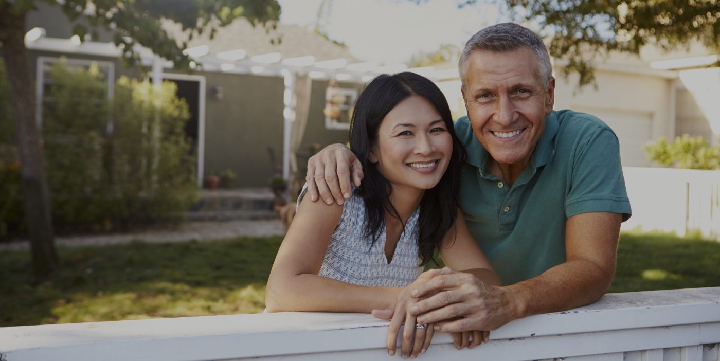 Man and woman in their front yard smiling with dental implants in San Marcos
