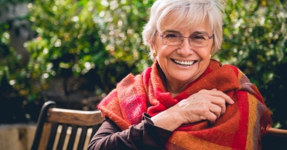 Older woman in multicolored shawl smiling outdoors