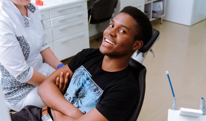Smiling man with arms crossed leaning back in dental chair