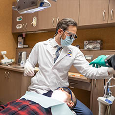 Dentist grabbing a dental instrument while treating a patient