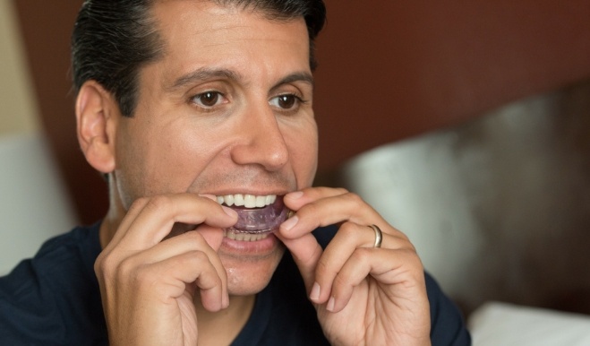 Man placing an oral appliance tray over his teeth